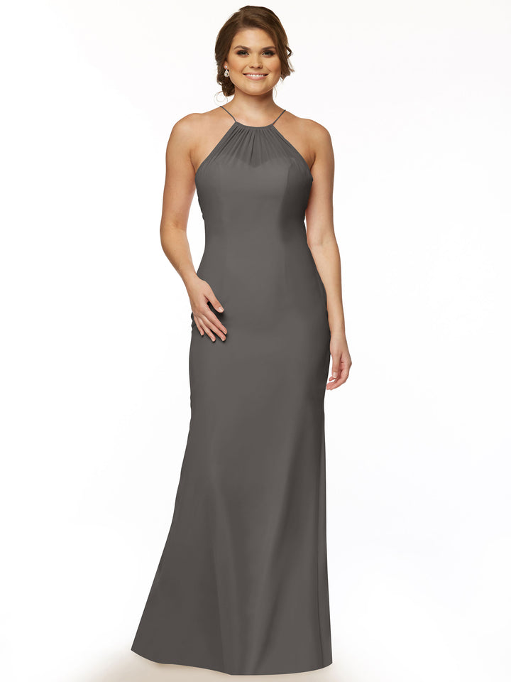 A woman smiles in the Avery Austin 80083, a sleeveless, floor-length charcoal gray halter dress with a keyhole back. She poses with one hand on her hip, hair in loose waves, against a plain white background.