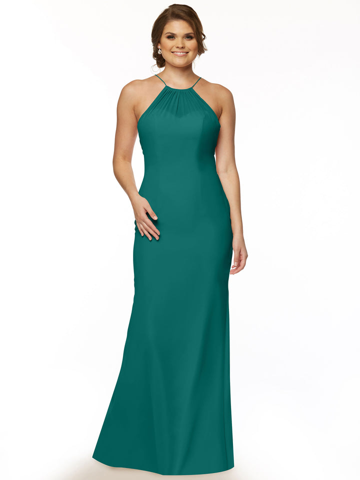 A woman wearing Avery Austin’s 80083— a sleeveless, floor-length teal chiffon halter dress with a keyhole back—stands against a plain white background, smiling softly with one hand on her hip.