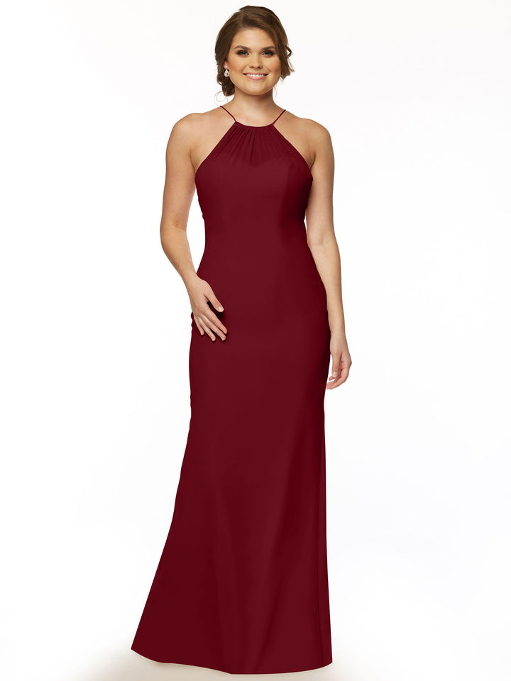 A woman wearing Avery Austin’s 80083—a sleeveless, floor-length burgundy halter dress with a keyhole back—stands smiling against a plain white background.