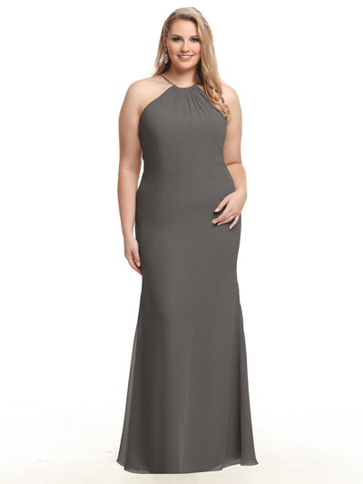A woman with long, side-styled blonde hair smiles against a white background, wearing the Avery Austin 80083: a sleeveless, floor-length dark gray halter dress with a keyhole back.