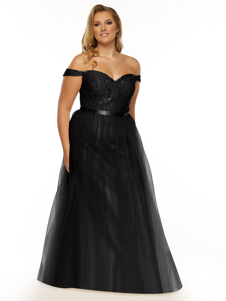 A woman wears Avery Austin’s 80085 dress in Black/Black, featuring a lace off-the-shoulder top, fitted sequined bodice, and flowing tulle A-line skirt, as she smiles gently against a plain white background.