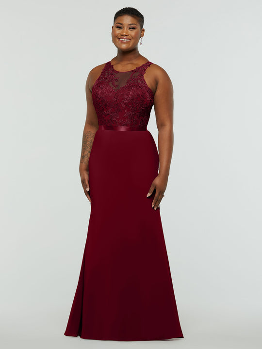 A smiling person models Avery Austin’s TH-80095, a sleeveless, floor-length burgundy gown with a fit-and-flare silhouette, lace bodice, and satin waistband, standing against a plain light gray background.