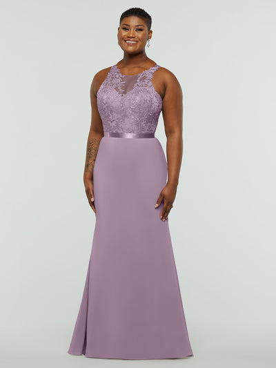 A woman smiles in Avery Austin’s 80095 mauve chiffon bridesmaid dress, featuring a lace bodice, illusion neckline, and satin waistband, against a plain light background.