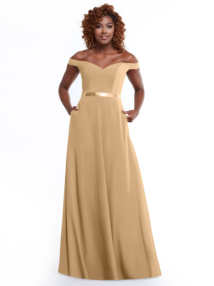 A woman models Avery Austin’s 80100—a gold, off-the-shoulder, floor-length A-Line dress with satin waistband and pockets—smiling against a white background.