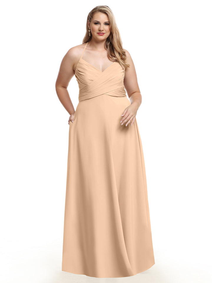 A woman models the Avery Austin TH-80101, a sleeveless blush A-line gown with a pleated bodice and V-neckline, fitted at the waist and floor-length, standing against a plain white background.