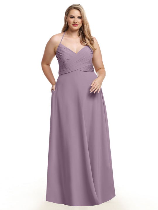 A woman wears Avery Austin's 80101, a lavender floor-length A-Line dress with a V-neckline and pleated bodice, standing with one hand in her pocket against a white background.