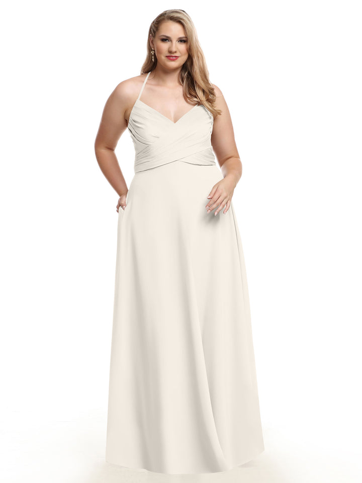 A woman wears Avery Austin’s 80101 ivory A-line dress featuring a pleated bodice, V-neckline, and flowing skirt, standing against a white background.