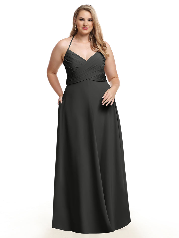 A woman models the Avery Austin 80101, a floor-length dark gray A-line dress with a halter neckline and pleated bodice, standing against a white background with one hand in her pocket.