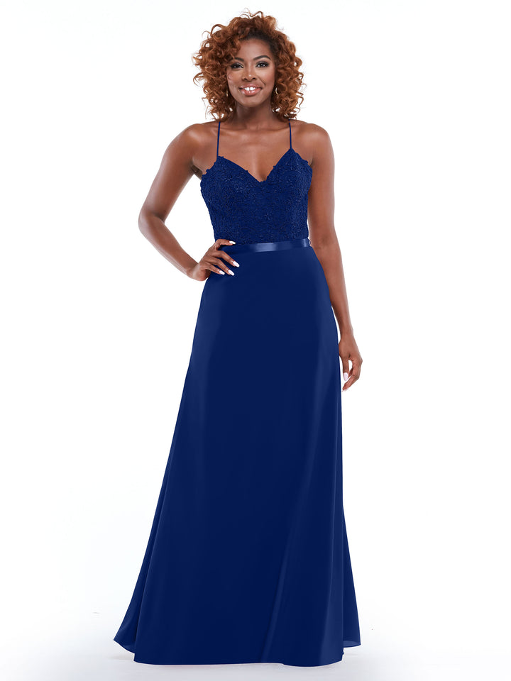 A woman wearing Avery Austin’s 80103—a sleeveless, floor-length navy gown with a fitted lace bodice, satin waistband, and A-line slit skirt—stands smiling against a white background.