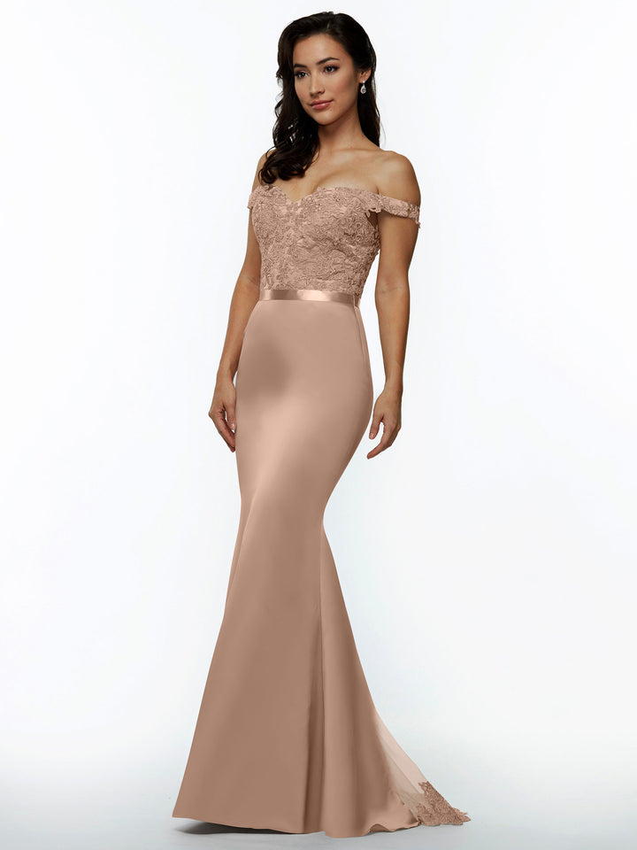 A woman poses against a plain white background in the Avery Austin TH-80104 bridesmaid dress in buff, featuring an off-the-shoulder lace bodice and a fitted satin skirt that flares at the bottom. She has long dark hair.