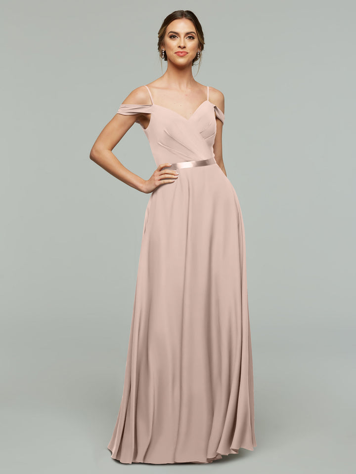 A woman poses against a plain background wearing Avery Austin’s 80106, a floor-length rose pink bridesmaid dress featuring off-the-shoulder thin straps, a fitted bodice with pleats, and a satin waistband.
