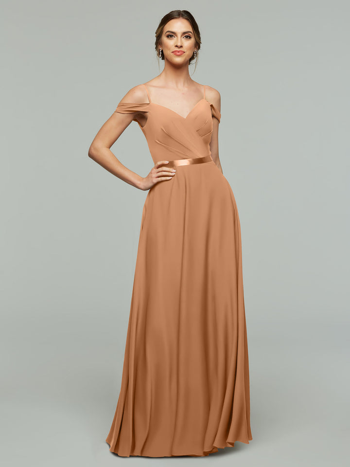 A woman poses against a plain background in Avery Austin’s 80106—a floor-length, copper off-the-shoulder bridesmaid dress with a fitted bodice and flowing A-line skirt—accessorized with earrings.