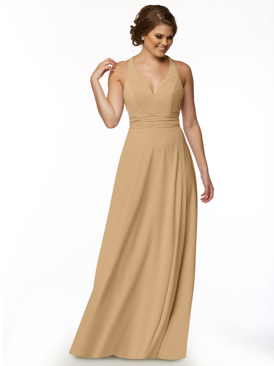 A woman smiles and looks down with one hand near her hair, modeling the Avery Austin 80107—a sleeveless, floor-length tan A-Line dress with a fitted bodice and feminine V-neckline—against a plain white background.