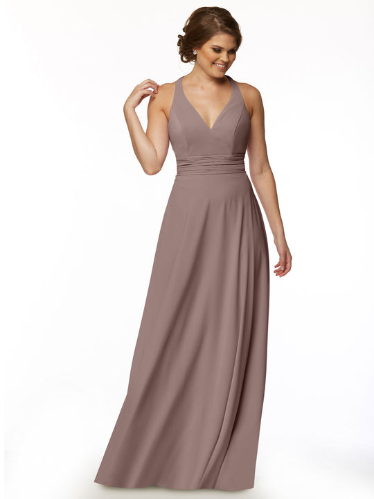 A woman stands against a white background, smiling and looking to the side while wearing the Avery Austin 80107— a mauve, floor-length, sleeveless A-line dress with a V-neckline and gathered waistband.