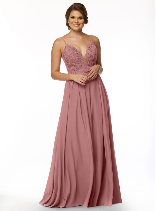 A woman in Avery Austin’s 80113, a sleeveless Dusty Rose floor-length gown with an A-line chiffon skirt, lace bodice, and deep V illusion neckline, stands smiling with hands clasped in front of her against a white background.