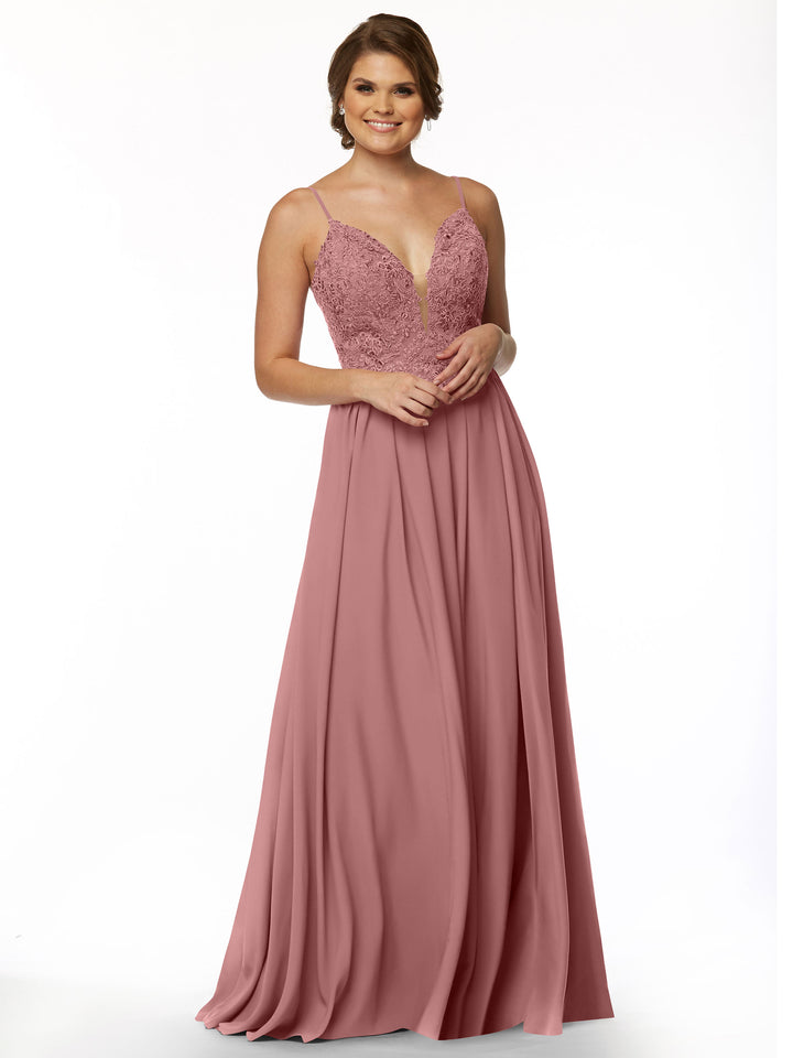 A woman in Avery Austin’s 80113, a sleeveless Dusty Rose floor-length gown with an A-line chiffon skirt, lace bodice, and deep V illusion neckline, stands smiling with hands clasped in front of her against a white background.