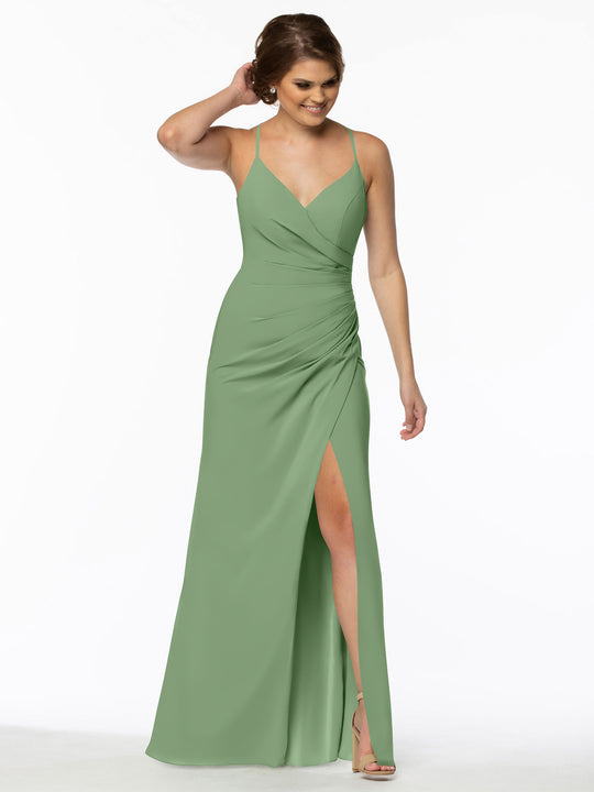 A woman wearing Avery Austin's TH-80114 bridesmaid dress in Dusty Sage, featuring a sleeveless V-neckline and high slit, stands against a white background, smiling and touching her hair.