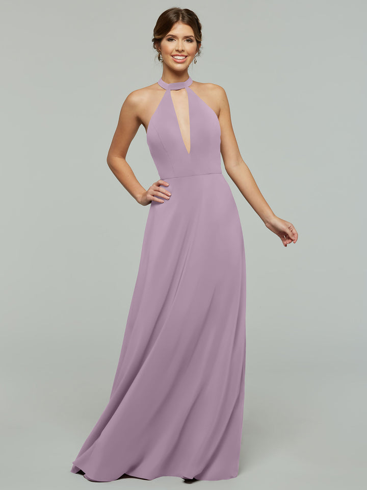 A woman in the Avery Austin 80115: a sleeveless, floor-length lavender A-line halter dress with a high neckline and front keyhole cutout, stands smiling against a plain light gray background.