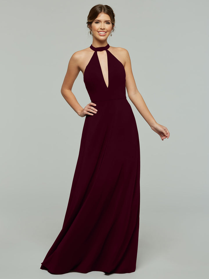 A woman wearing Avery Austin’s 80115— a sleeveless, floor-length dark burgundy halter A-line dress with a keyhole cutout—smiles against a plain gray background.