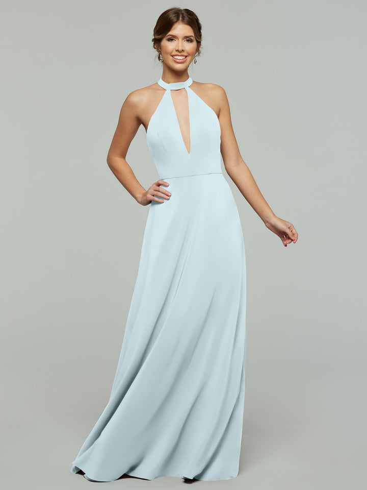 A woman smiles as she models Avery Austin’s sky blue, floor-length halter A-Line dress (style 80115) with a keyhole neckline and flowing skirt, set against a plain gray background.