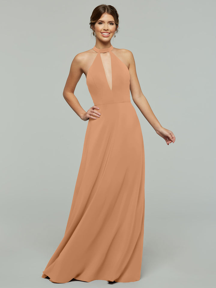 A woman smiles in the Avery Austin 80115 dress, a sleeveless, floor-length peach halter A-line gown with a deep V cutout. The flowing skirt and her loose updo stand out against the plain light gray background.