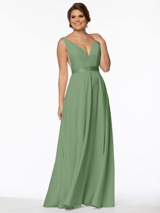 A woman wearing Avery Austin's 80117—a sleeveless, floor-length sage green A-line gown with a deep V-neckline and fitted waist—smiles against a plain white background.