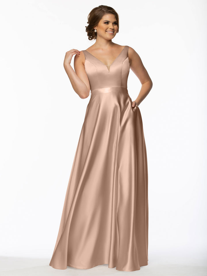 A woman smiles in Avery Austin’s 80118—a long satin bridesmaid dress with a V-neckline and subtle pleats—against a plain white background.