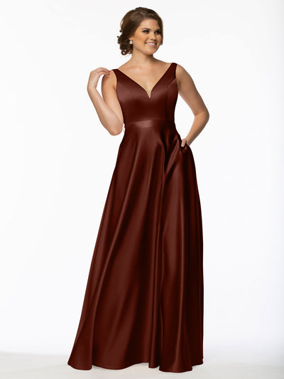 A woman poses against a white background wearing Avery Austin's 80118 sleeveless bridesmaid dress in burgundy satin, featuring a V-neckline and handy pockets.
