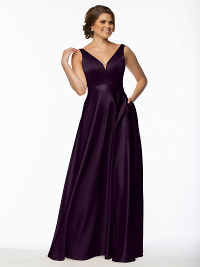 A woman smiles in the Avery Austin 80118 bridesmaid dress, featuring a sleeveless V-neckline, floor-length satin design with pockets, in Eggplant color, against a plain white background.