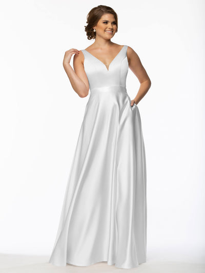 A woman models Avery Austin's long satin bridesmaid dress (Style 80118) with a V-neckline and fitted waist, smiling against a white background, one hand at her side and the other touching her hair.