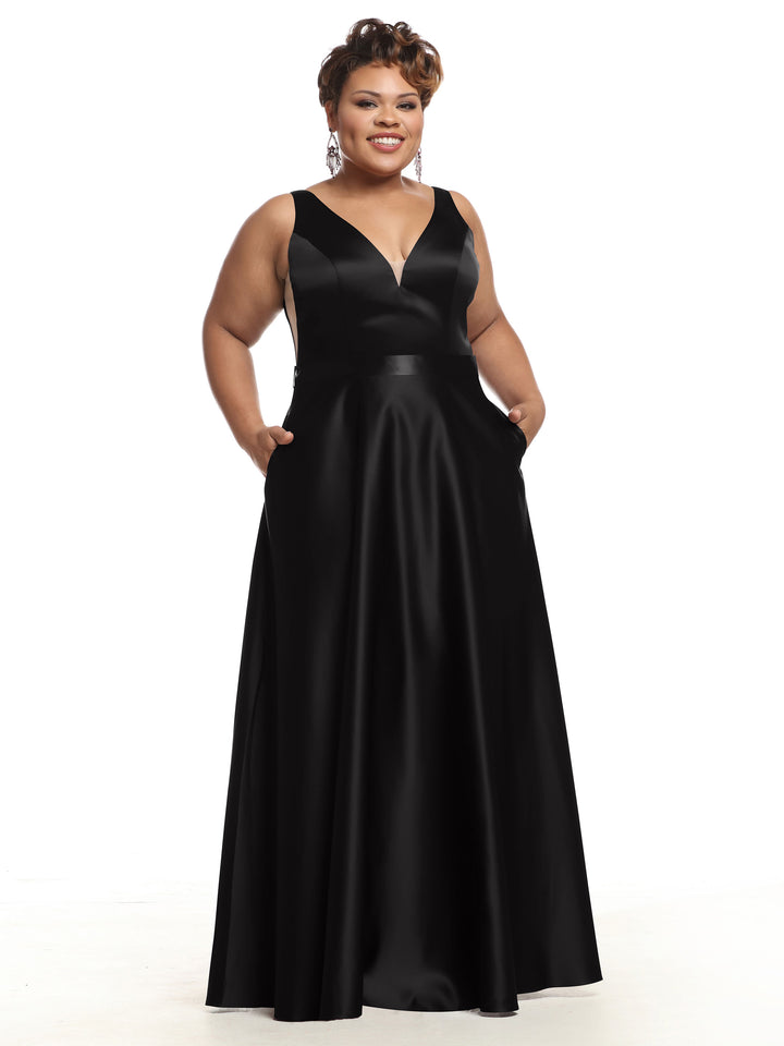 A woman stands smiling with her hands in the pockets of the Avery Austin 80118 black satin sleeveless bridesmaid dress, featuring a floor-length skirt and deep V-neckline, against a plain white background.