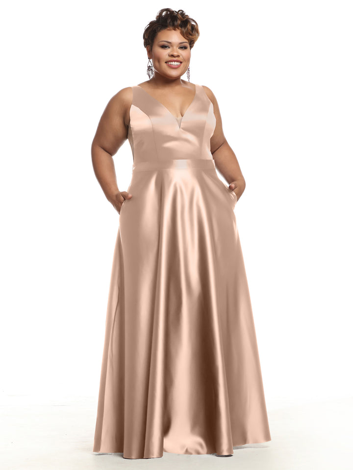 A woman smiles against a white background wearing Avery Austin’s 80118—a sleeveless, floor-length satin bridesmaid dress with a deep V-neckline and pockets.