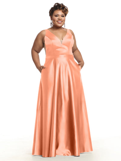A woman smiles in Avery Austin’s 80118 bridesmaid dress, featuring a sleeveless V-neck design with pockets in dark coral satin, set against a plain white background.