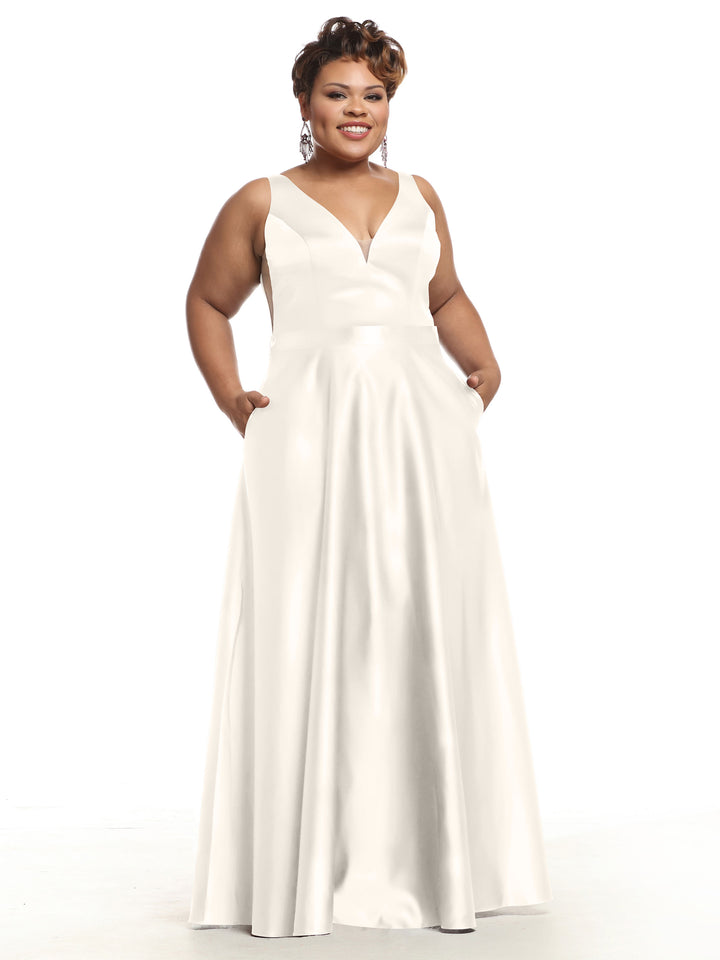 A smiling woman wears Avery Austin’s sleeveless, floor-length white satin bridesmaid dress (style 80118) with pockets and a deep V-neckline, standing against a plain white background.