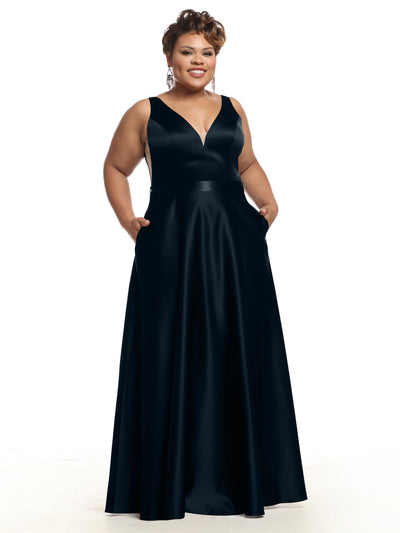 A smiling woman showcases Avery Austin's 80118 satin bridesmaid dress in Midnight, featuring a deep V-neckline and pockets, set against a plain white background.
