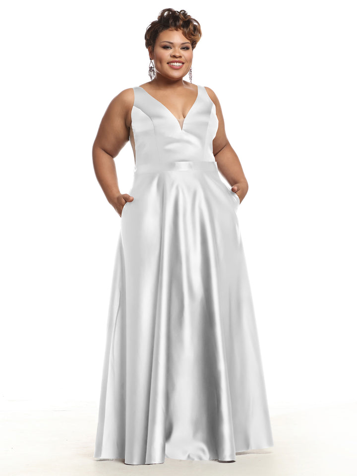 A smiling woman wears Avery Austin’s silver 80118: a sleeveless, floor-length satin bridesmaid dress with pockets and a deep V-neckline, standing against a plain white background.
