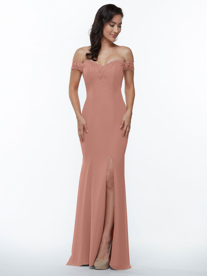 A woman models the Avery Austin TH-80121, an off-the-shoulder blush pink bridesmaid dress with a fitted bodice, lace details, and a thigh-high slit. She stands against a plain white background in beige high heels with long dark hair.