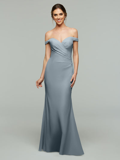 A woman smiles in front of a plain light gray background, wearing Avery Austin’s 80122—a light blue, off-the-shoulder bridesmaid dress with a fitted bodice and gentle draping.