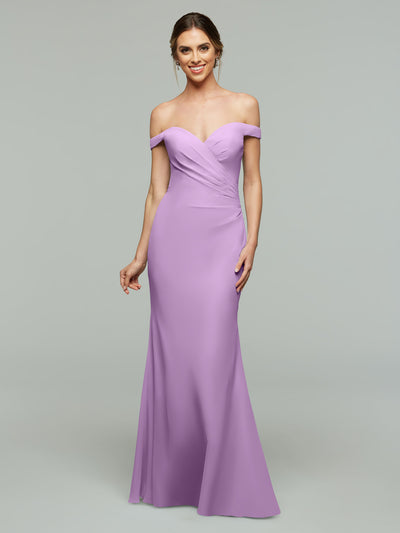 A woman smiles in the Avery Austin 80122, a fitted, off-the-shoulder lavender bridesmaid dress with a sweetheart neckline and floor-length skirt, elegantly draped against a plain light gray background.