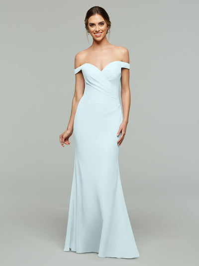 A woman models the Avery Austin 80122, a light blue off-the-shoulder bridesmaid dress with a fitted bodice, standing against a plain gray background and smiling gently with her hair in an elegant updo.