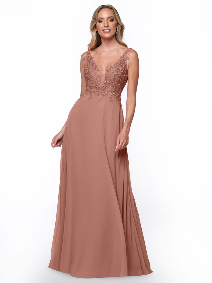 A woman wearing Avery Austin style 80128, a dusty rose chiffon bridesmaid dress with lace bodice, deep V neckline, and floor-length skirt stands against a plain white background, smiling gently.