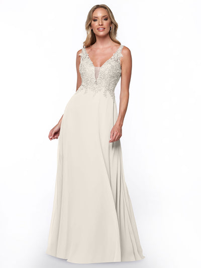 A woman wearing Avery Austin style 80128, a long bridesmaid dress with a deep V-neckline and intricate lace bodice, stands against a plain white background.