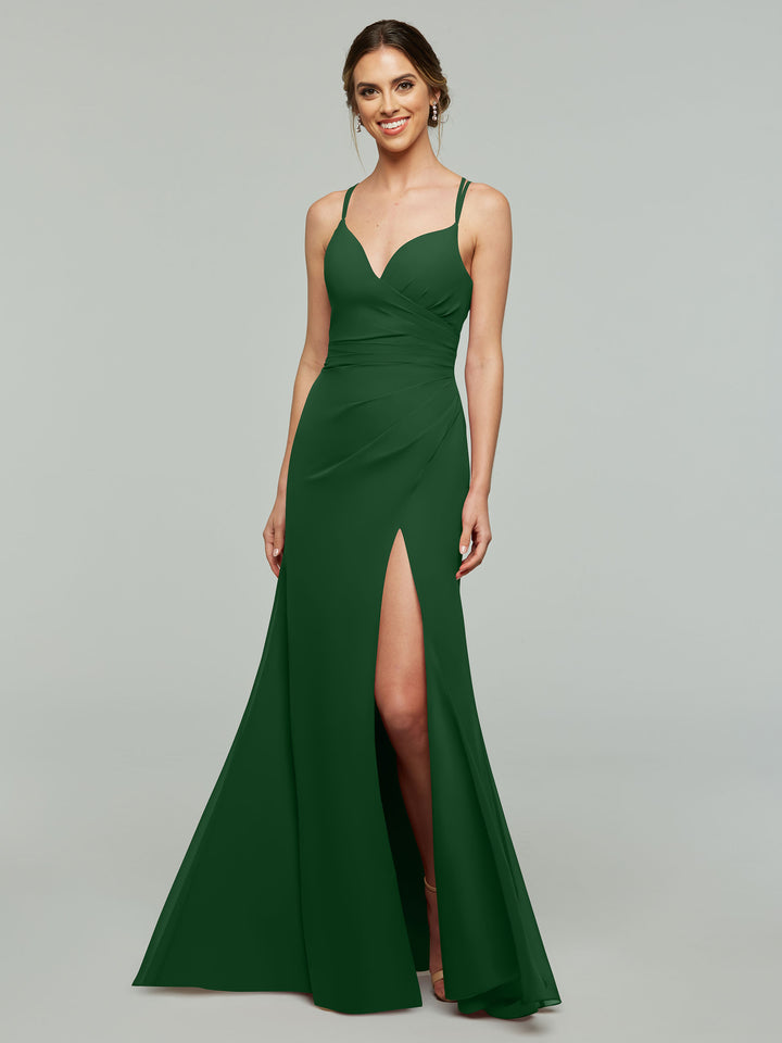 A woman in Avery Austin’s TH-80130 hunter green sleeveless chiffon bridesmaid dress, featuring a v-neck, fitted bodice, and high slit, smiles against a light gray background.