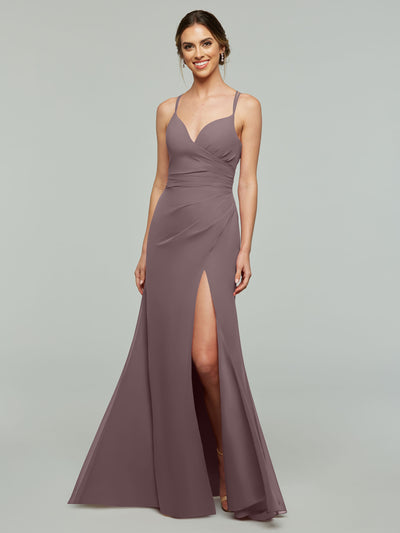 A woman smiles against a light gray background in the Avery Austin 80130—a mauve, floor-length chiffon bridesmaid dress featuring thin straps, a v-neckline, ruched bodice, and high slit.