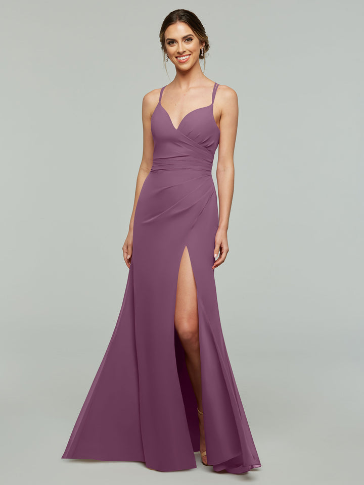 A woman wears the Avery Austin 80130 floor-length, sleeveless mauve v-neck chiffon bridesmaid dress with a high side slit, standing against a plain light gray background and smiling at the camera.