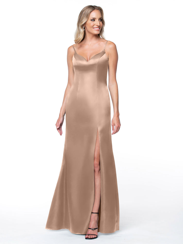 A woman smiles against a white background wearing Avery Austin’s 80132, a sleeveless champagne satin fit and flare dress with a V-neckline and high slit skirt.