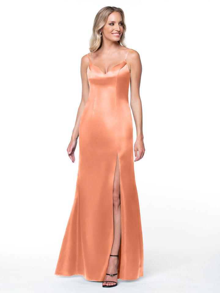 A woman models the Avery Austin 80132: a sleeveless peach satin dress with thin straps, an intricate back, and a high slit, standing against a plain white background.