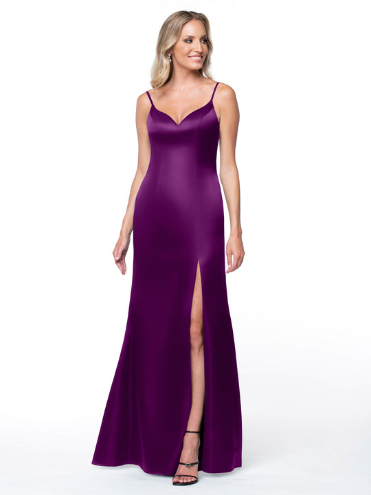 A woman in the Avery Austin TH-80132 sleeveless, purplish satin dress with thin straps and a thigh-high side slit stands smiling against a plain white background.