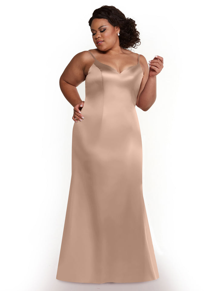 A woman with dark hair in an updo models Avery Austin’s 80132—a sleeveless, floor-length fit-and-flare dress with a sweetheart neckline and intricate back—posing confidently against a white background.