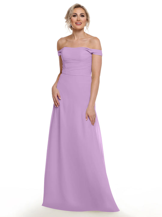 A woman with blonde hair styled in an updo wears Avery Austin’s floor-length, light purple off-the-shoulder chiffon dress (80136), standing and smiling against a plain white background.